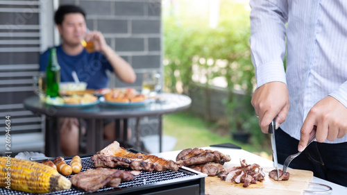 Group of friends Two young man enjoying grilled meat and raise a glass of beer to celebrate the holiday festival happy drinking beer outdoors and enjoyment at home