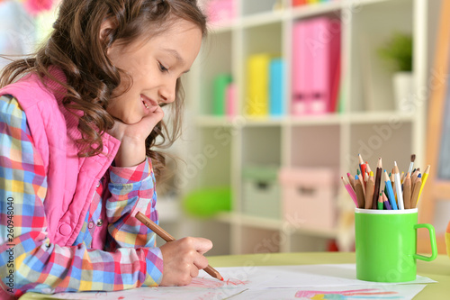 Cute little girl drawing while sitting at table