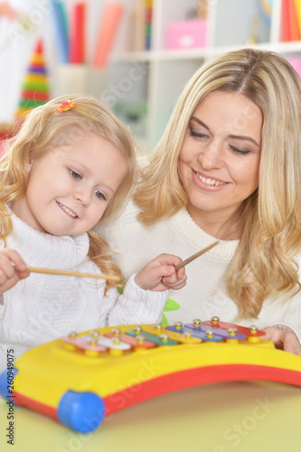 Close up portrait of mother with little daughter playing on musical instrument