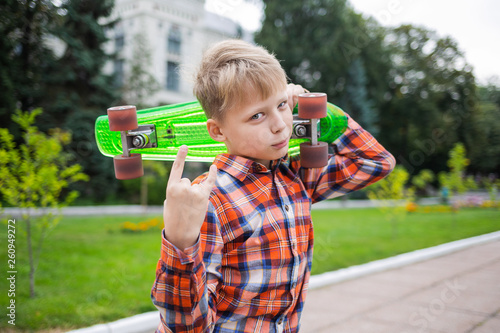 White child skating on green plastic rollerskate in city. Portrait of cute cool kid of 10 years having fun outdoors on summer or autumn evening. Horizontal color photography. photo