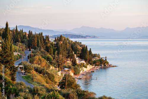 Summer sunrise on coast, Corfu island, Greece. View of the coast, the capital of the island and Albanian mountains
