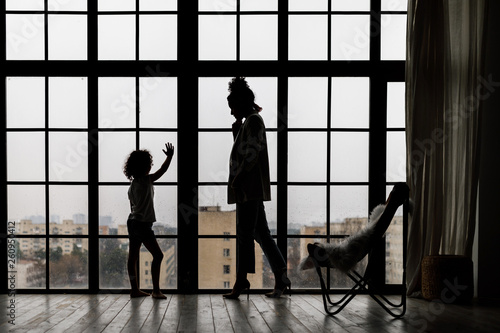 Side view of loving mother and daughter embracing by window