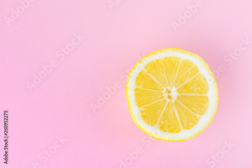 yellow sliced lemon on a pastel pink monochromatic background