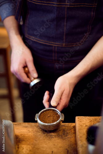 Barista presses ground coffee using tamper in a coffe shop © nagaets