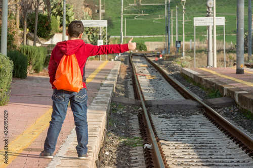 Young hitchhiker waiting of the train, standing on railway © puckillustrations