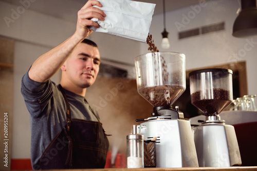 Barista makes espresso in cafe. Barista grind beans with coffee machine. Coffee grinder grinding roasted beans in powder.