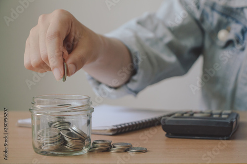 Business woman hand putting coin into glass jar.saving money and financial concept. Financial planning for the future.