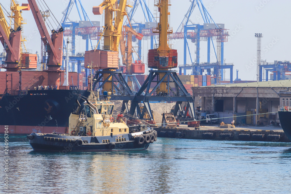 Tugboat at the bow of cargo ship , assisting the vessel to maneuver in Sea Port of Odessa, Ukraine
