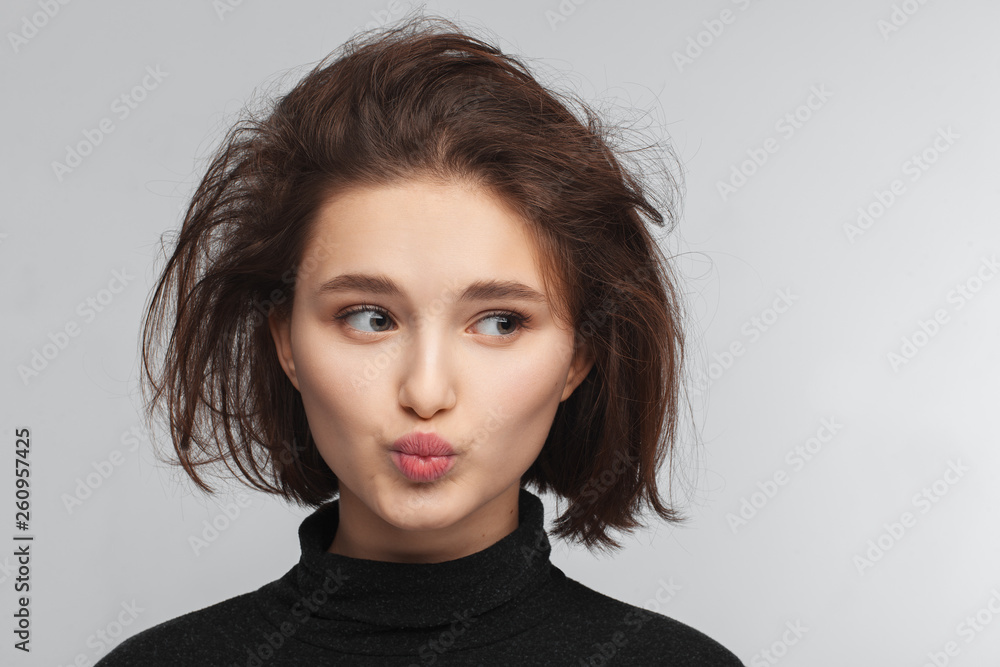Portrait of a beautiful teen girl in a black sweater on a gray background. Combed up hair Portrait of a beautiful teen girl in a black sweater on a gray background. Combed up hair