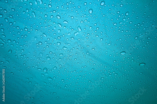 Rain drops on the solid abstract blue background. Bright shiny pattern of raindrops