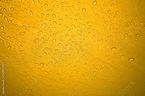 Rain drops on the solid abstract yellow background. Bright shiny pattern of raindrops