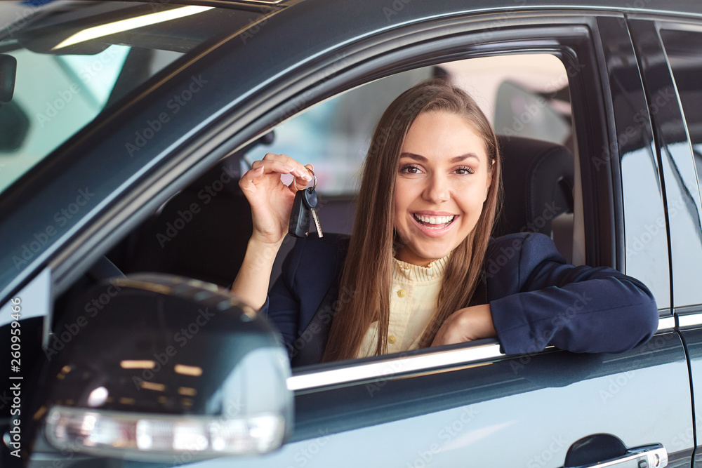 A female driver smiles and holds car keys. A female driver smiles and holds car keys.