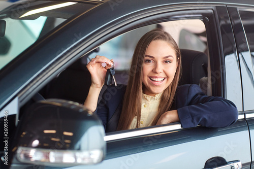 A female driver smiles and holds car keys.