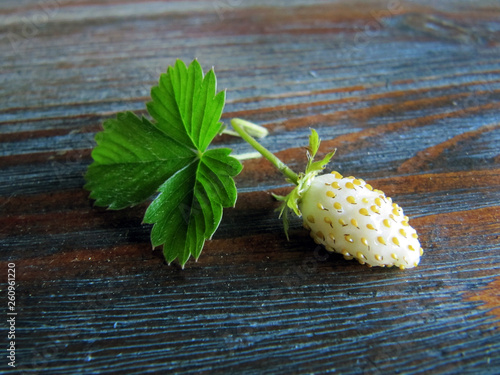 Wild strawberries with leaves on wooden table.  