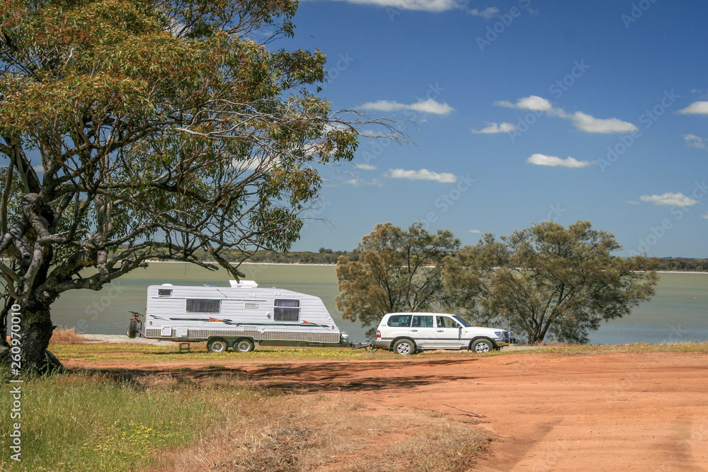 Four wheel drive vehicle and large caravan at roadside stop next to a lake in the outback of Australia.