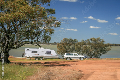 Four wheel drive vehicle and large caravan at roadside stop next to a lake in the outback of Australia.