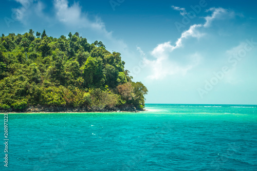 Beautiful paradise green island in the ocean. Tropics. Thailand Andaman Sea. Seascape with azure water and an island with many plants.