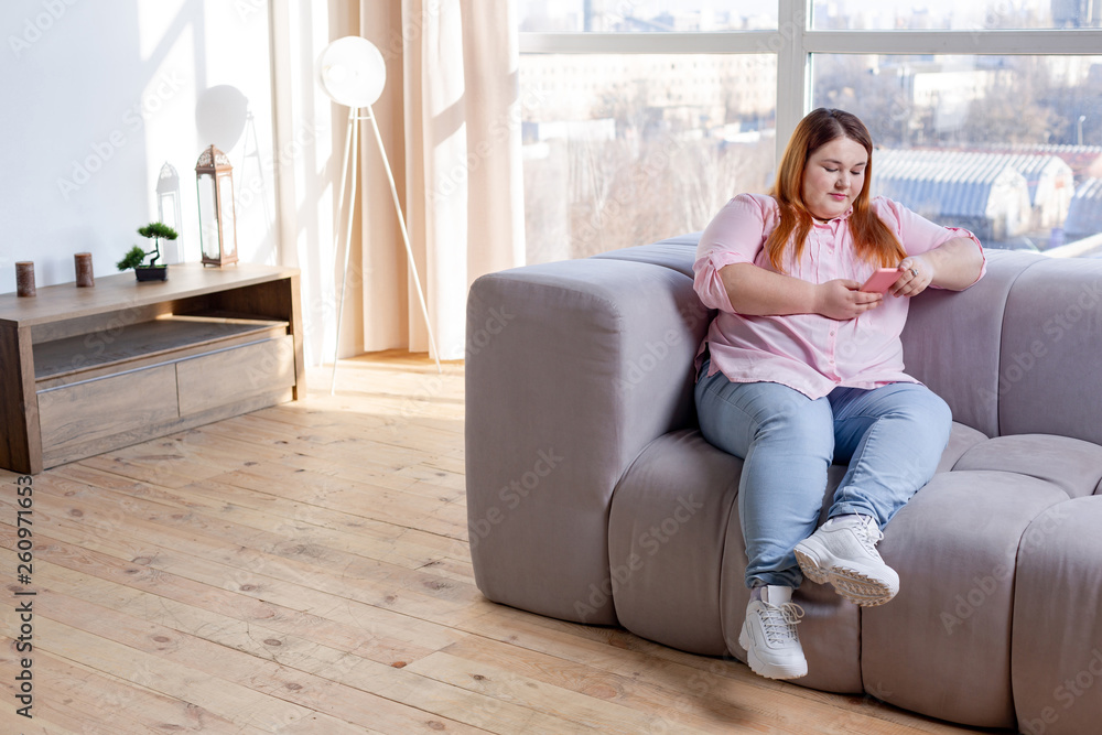 Pleasant plump woman looking at her phone screen Pleasant plump woman looking at her phone screen