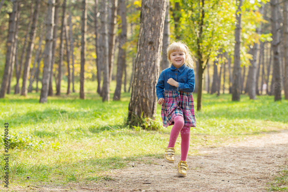 little happy girl with a smile on her face jumping and playing outdoors little happy girl with a smile on her face jumping and playing outdoors
