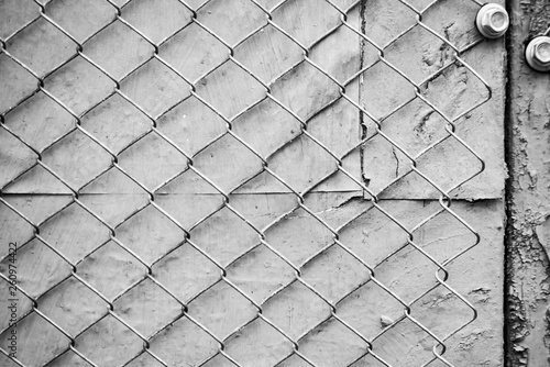 Monochrome metal mesh fence attached with a screw to the wall