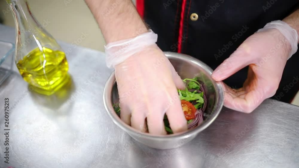 A chef working in the kitchen. Making a salad. Mixing ingredients A chef working in the kitchen. Making a salad. Mixing ingredients