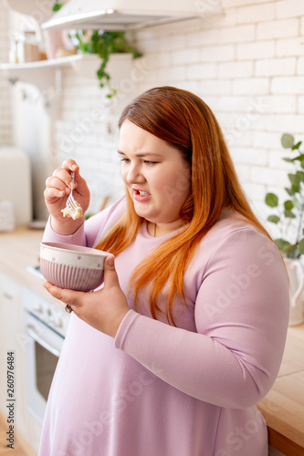 Fotografija Unhappy plump woman looking at the oatmeal