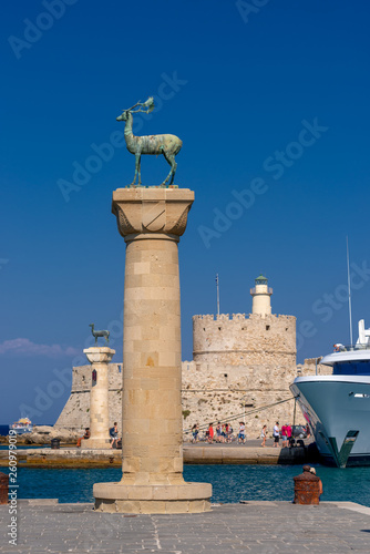 Rhodes, Greece - August 2016: Hirschkuh statue at the entrance from inner embankment in the Mandraki old harbour of the City of Rhodes, with Fort of Saint Nicholas in background.