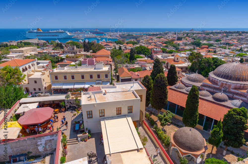 Obraz premium Panoramic view of the Rhodes medieval old city, with the new Mandraki harbour in the background, full of cruise ships. Popular summer holiday destination in the Greek Dodecanese.