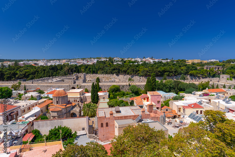 Panoramic view of the Rhodes medieval old city surrounded by ancient stone defensive walls, with the new town and Acropolis in the background. Popular summer holiday destination in the Greece.