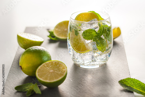 Glass of mojito cocktail on a dark board with fresh peppermint leaves and lime fruits  photo