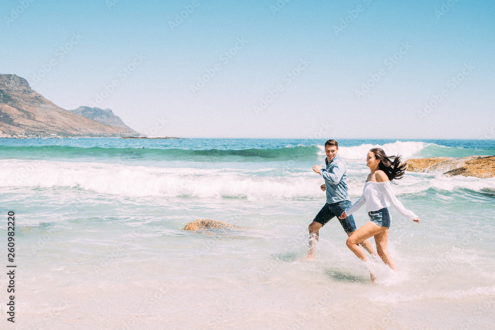 Junges Paar voller Liebe, Freude und Freiheit am Strand im sonnigen Kapstadt