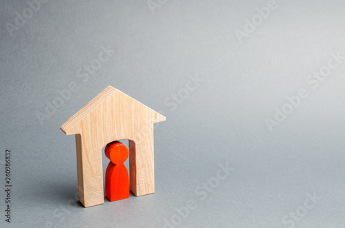 Miniature wooden house with a tenant inside. The concept of renting a house or apartment. Affordable housing. Mortgage. Home loan. Real estate and property. Lodger. Insurance. Moving photo