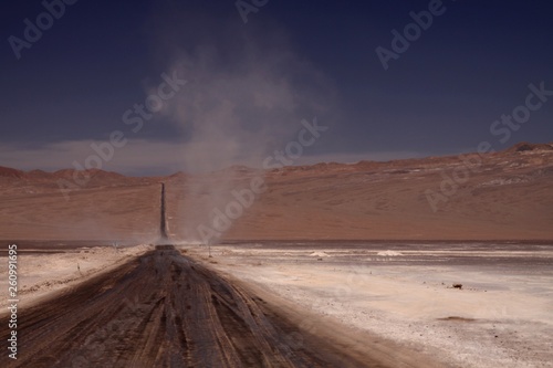 Vortex in the horizon of endless dirt road through waste barren plane in Atacama desert, Chile