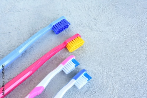 Colorful family toothbrushes with selective focus on grey cement background. Dental concept with male, female and kids toothbrush on neutral backdrop. New toothbrushes for cleaning teeth.