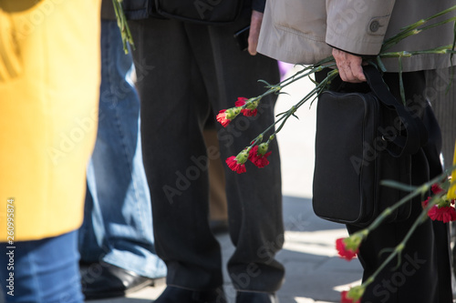 Bouquet of red carnations in man hand at Victory Day celebrations; focus on flower
