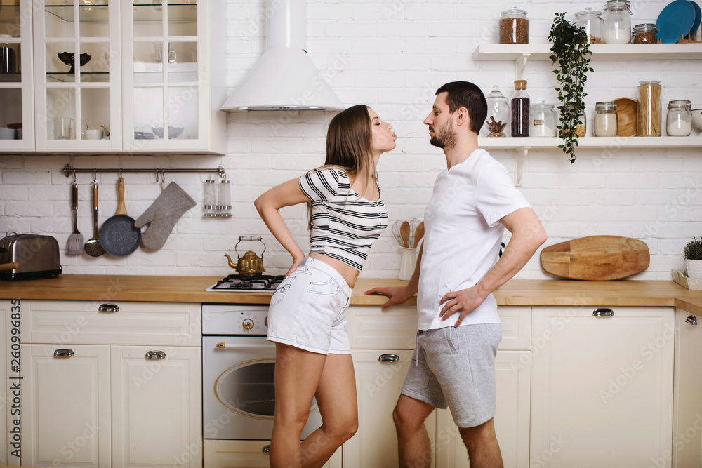 Young couple having nice time together at the kitchen on weekend and preparing food, washing dishes, making coffee in their new house Young couple having nice time together at the kitchen on weekend and preparing food, washing dishes, making coffee in their new house
