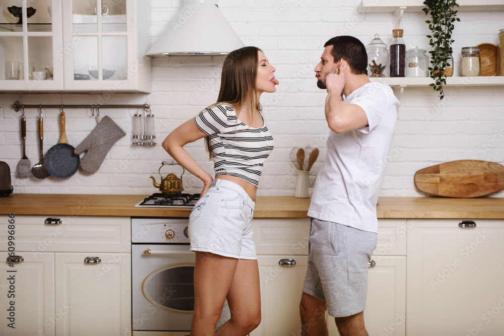Young couple having nice time together at the kitchen on weekend and preparing food, washing dishes, making coffee in their new house Young couple having nice time together at the kitchen on weekend and preparing food, washing dishes, making coffee in their new house