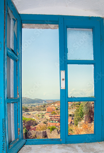 View of the city from the window of the building in the fortress of the old bar, Montenegro. Blue old window among white walls. Summer.