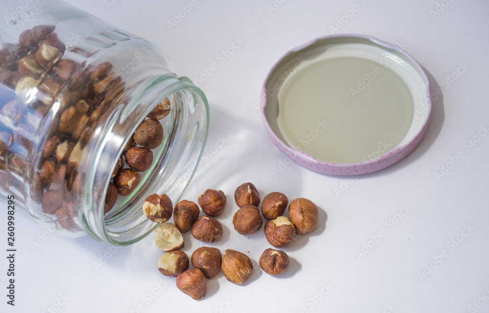 Raw hazelnuts scattered from glass jar isolated on white background. Fresh organic brown nuts in studio interior. Many lots of pieces of beer nuts texture pattern. Common farm crop of Black Sea Region Raw hazelnuts scattered from glass jar isolated on white background. Fresh organic brown nuts in studio interior. Many lots of pieces of beer nuts texture pattern. Common farm crop of Black Sea Region