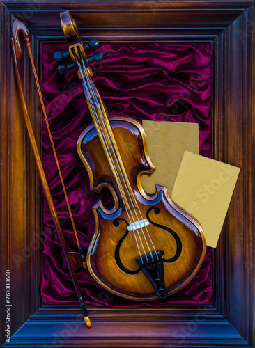 Violin and bow in a wooden frame on a red cloth