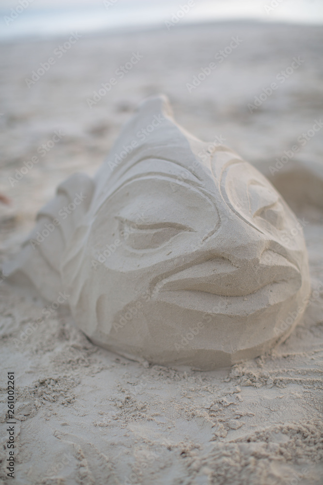 man has modeling an artistic fish sculpture out of sand at a white beach a summer vacation scene man has modeling an artistic fish sculpture out of sand at a white beach a summer vacation scene