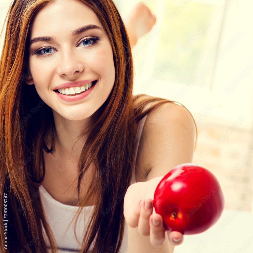 Smiling woman with red apple, indoors Smiling woman with red apple, indoors