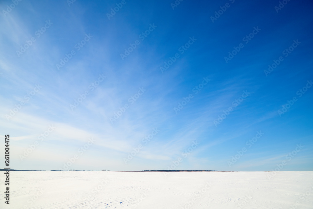 Blue sky with white clouds over white snowy field in winter Blue sky with white clouds over white snowy field in winter