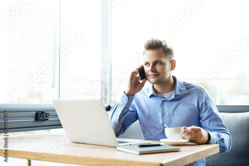 Stylish young man calling by the phone to solve business problems. Online consultation by phone. Freelancer discussing the development and planning of his online project. Outsourcing. Mobile services.