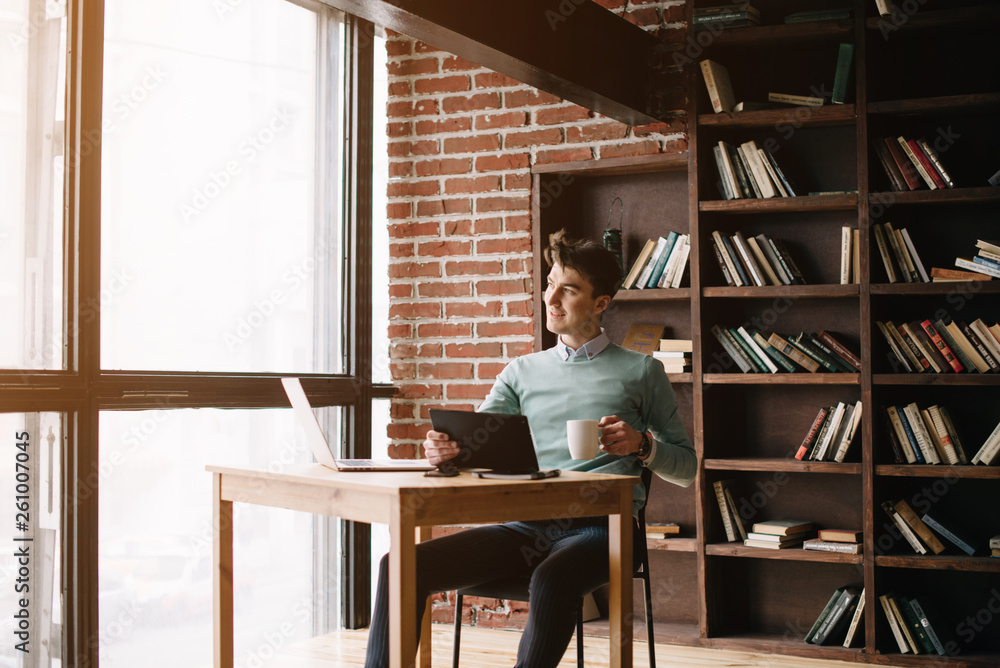 Young handsome student typing on his notebook his diploma. Student discussing on the phone universities's timetable. Education online. Work on freelance. Software development.