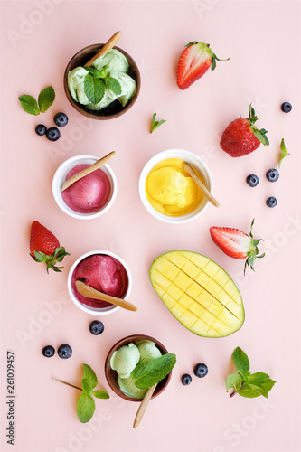 Ice cream set on a light pink background. Berry  pistachio  mango ice cream in bowls