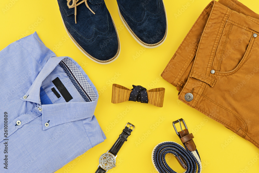 Casual outfits for man clothing with blue shirt, mustard jeans, belt,  watch, blue shoes and accessories isolated on yellow background, top view.  Trendy fashion male flatlay background Photos | Adobe Stock