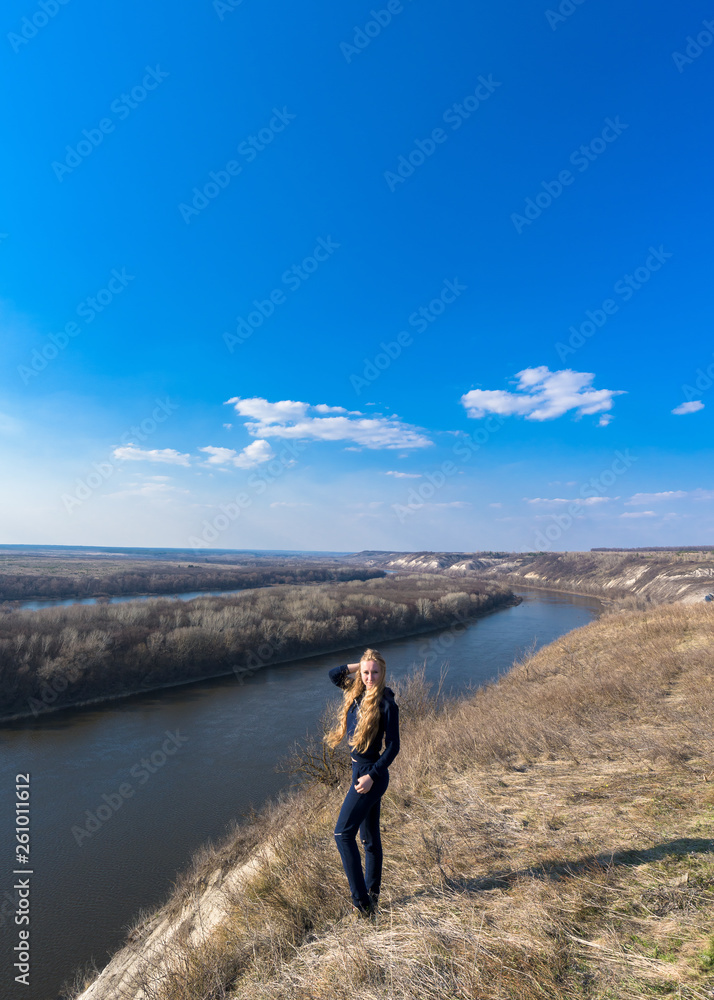 girl on the river Bank. wide channel, blue sky. mountain shore