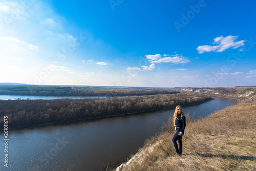 girl on the river Bank. wide channel  blue sky. mountain shore