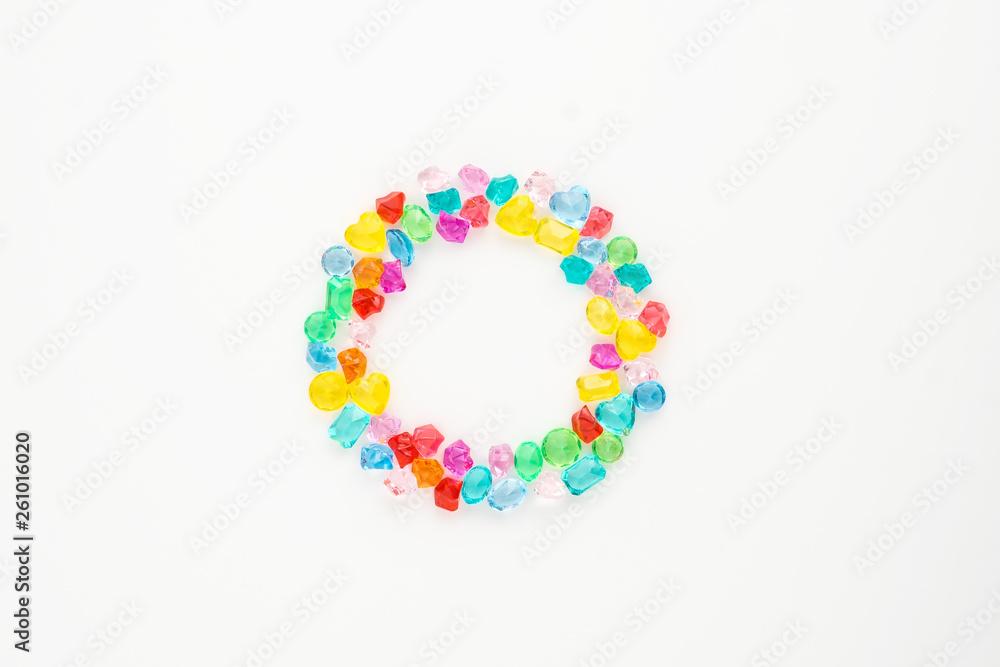A scattering of many small different gems on a white background. Different shapes. Multicolor. Glasses collected in the ring. A scattering of many small different gems on a white background. Different shapes. Multicolor. Glasses collected in the ring.